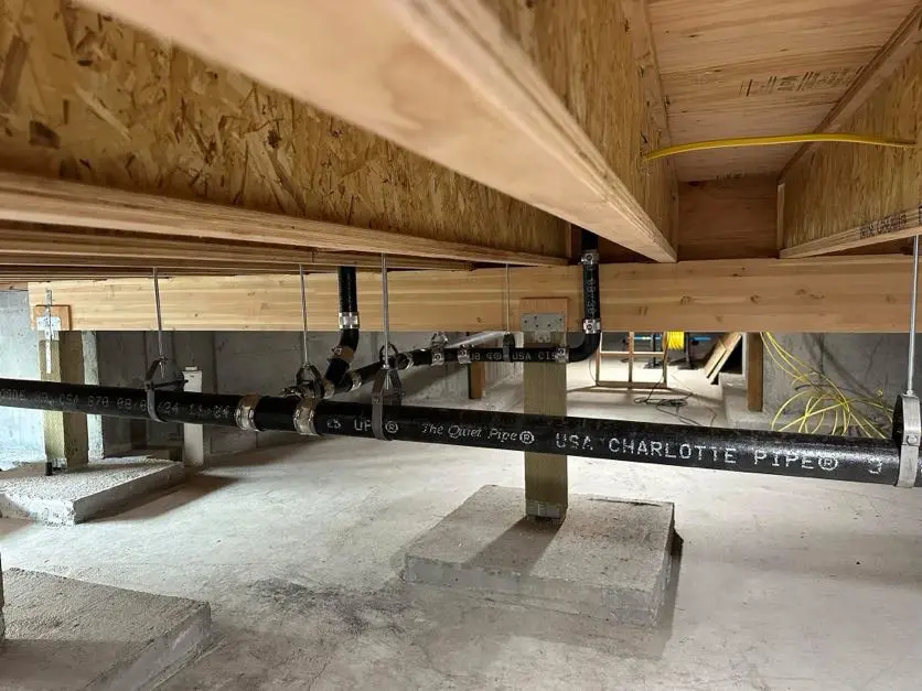 Wooden beams and PVC piping under construction.